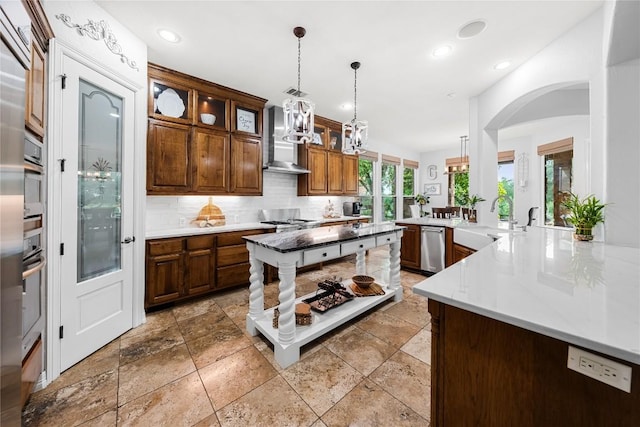 kitchen with stainless steel dishwasher, wall chimney range hood, arched walkways, a sink, and backsplash
