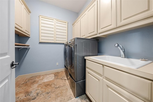 washroom featuring baseboards, stone finish flooring, a sink, cabinet space, and independent washer and dryer