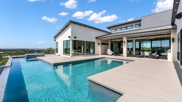 back of property featuring a standing seam roof, stucco siding, metal roof, and an outdoor pool