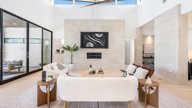 bathroom featuring a freestanding tub, a tiled fireplace, wood finished floors, and a towering ceiling
