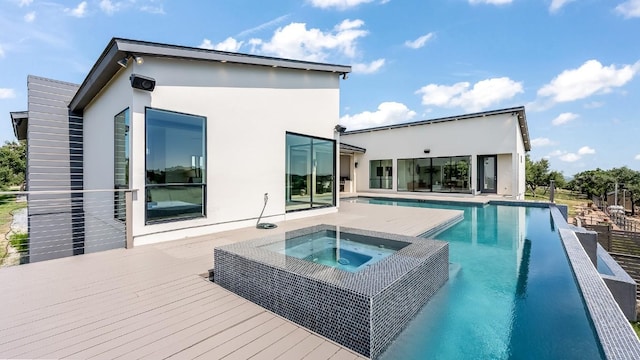 rear view of house with stucco siding, a pool with connected hot tub, and a deck