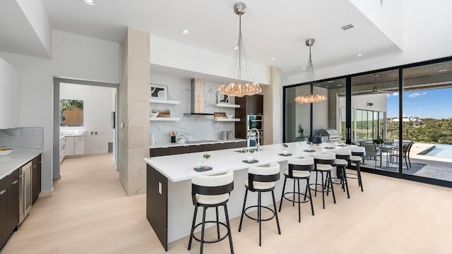 kitchen with open shelves, light wood-style floors, light countertops, a kitchen breakfast bar, and a large island