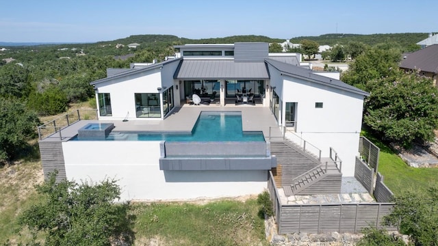 rear view of house with a pool with connected hot tub, a fenced backyard, a patio area, and stucco siding