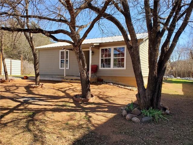 single story home featuring fence and metal roof