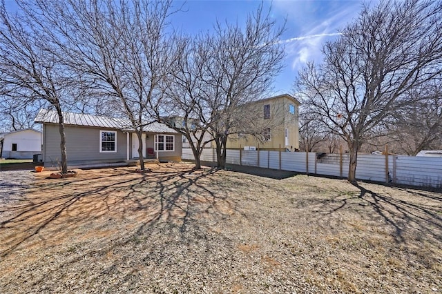 back of property featuring fence and metal roof