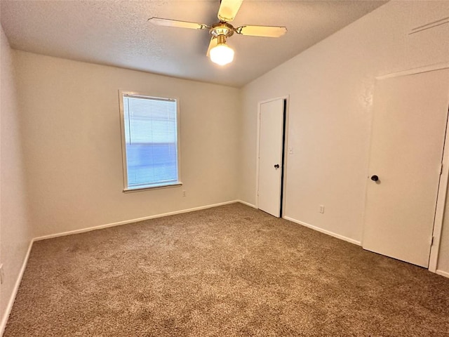 carpeted empty room with baseboards, ceiling fan, and a textured ceiling