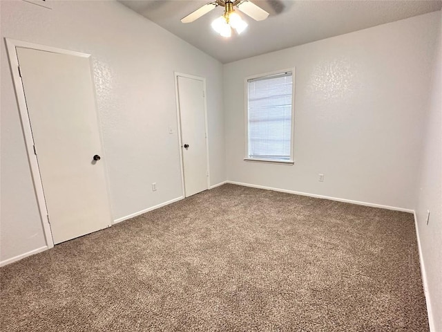 unfurnished bedroom featuring baseboards, a ceiling fan, carpet, and vaulted ceiling