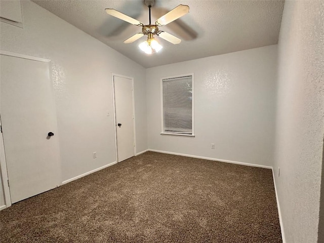 unfurnished bedroom with a textured ceiling, carpet, a ceiling fan, baseboards, and vaulted ceiling