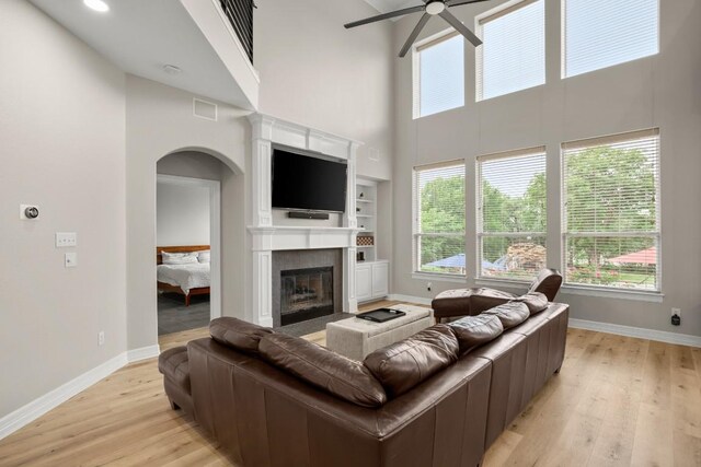 601 Scenic Path, Leander, TX 78641 - living room featuring a high ceiling, a ceiling fan, arched walkways, light wood-style floors, and baseboards