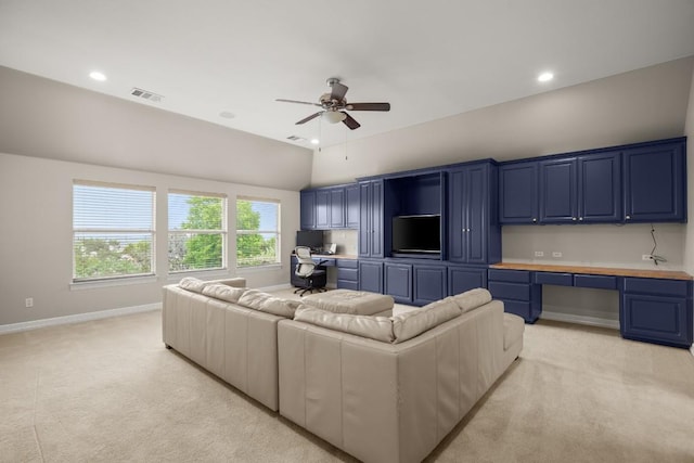 living room with built in study area, ceiling fan, and light colored carpet