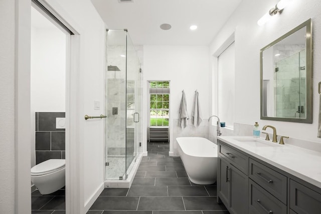 bathroom with tile patterned flooring, vanity, a freestanding tub, toilet, and a stall shower