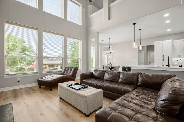living area featuring light wood-style floors, a notable chandelier, and a healthy amount of sunlight