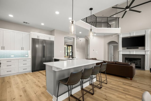 kitchen with ceiling fan, a sink, high end refrigerator, a towering ceiling, and visible vents