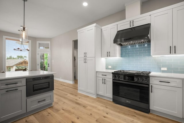 kitchen with light countertops, black gas range oven, under cabinet range hood, and tasteful backsplash