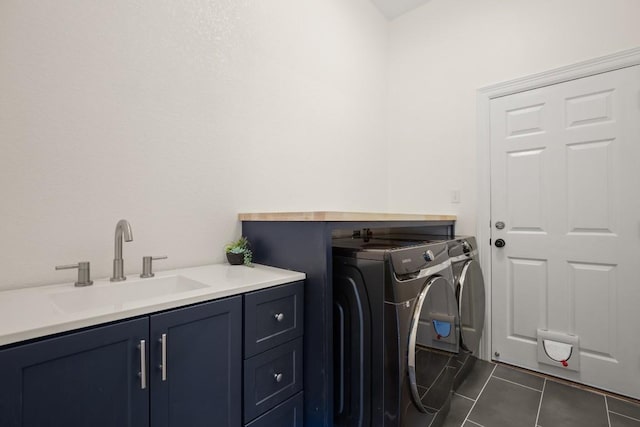 laundry room featuring a sink, dark tile patterned floors, cabinet space, and washing machine and clothes dryer