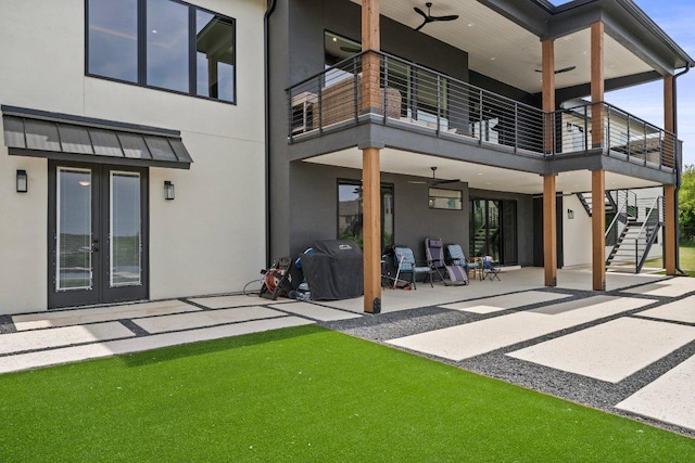 rear view of property featuring stucco siding, stairway, a balcony, french doors, and a patio