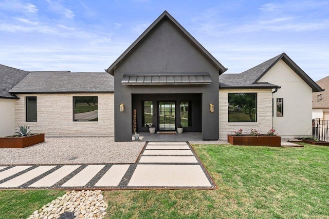 rear view of house featuring roof with shingles, stucco siding, a yard, and stone siding