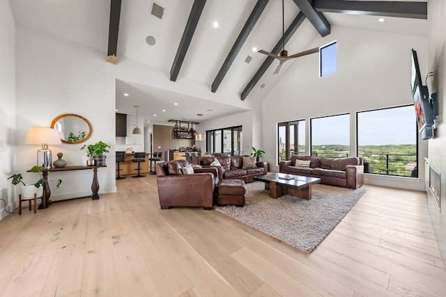 living room with high vaulted ceiling, beamed ceiling, light wood-style flooring, and visible vents
