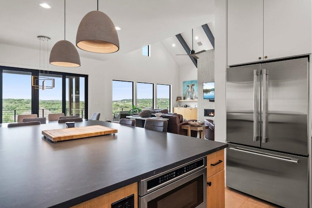 kitchen featuring dark countertops, appliances with stainless steel finishes, high vaulted ceiling, recessed lighting, and open floor plan