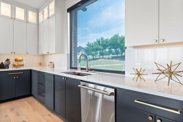 kitchen with a sink, stainless steel dishwasher, light wood finished floors, and white cabinetry