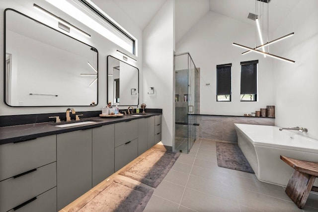 bathroom featuring double vanity, a towering ceiling, tile patterned flooring, a stall shower, and a sink