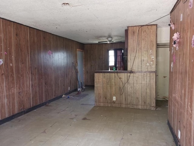 kitchen featuring wooden walls, brown cabinetry, and a ceiling fan