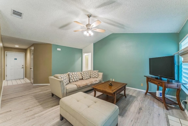 living room with visible vents, light wood-style floors, baseboards, ceiling fan, and a textured ceiling