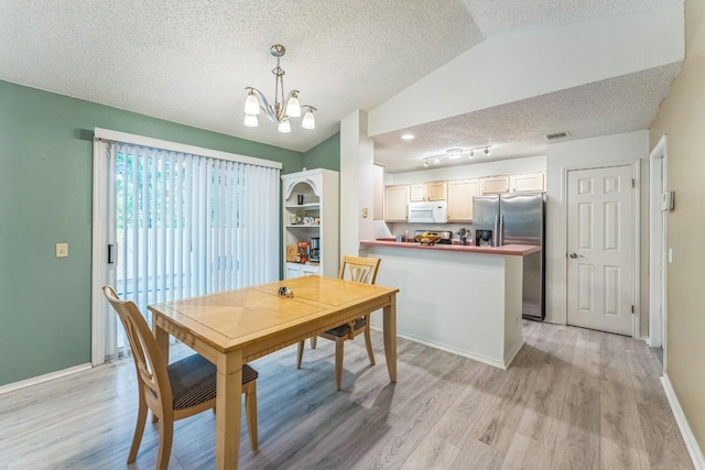 dining space featuring an inviting chandelier, a textured ceiling, baseboards, light wood-type flooring, and vaulted ceiling