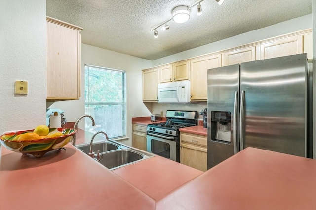 kitchen with track lighting, light brown cabinetry, a textured ceiling, a sink, and appliances with stainless steel finishes