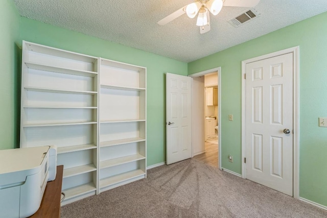 unfurnished bedroom featuring a ceiling fan, a textured ceiling, visible vents, baseboards, and carpet flooring