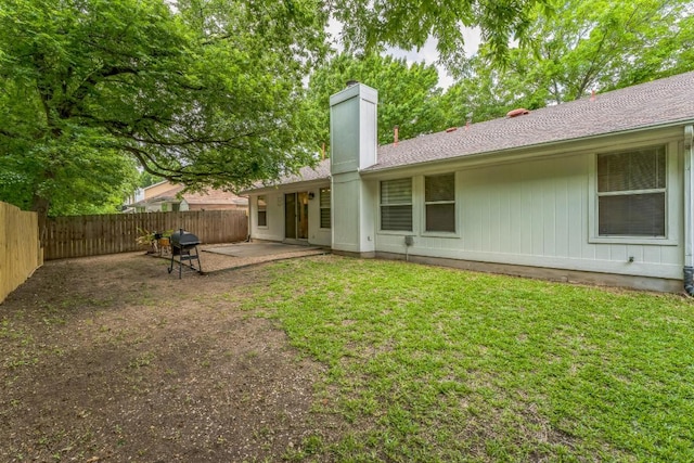 rear view of house with a fenced backyard, a patio, a chimney, and a yard