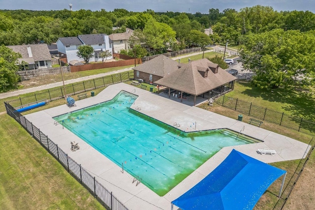 pool featuring a yard, a forest view, and fence
