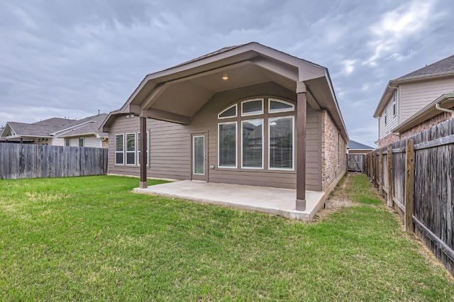 back of house with a fenced backyard, a patio, and a yard
