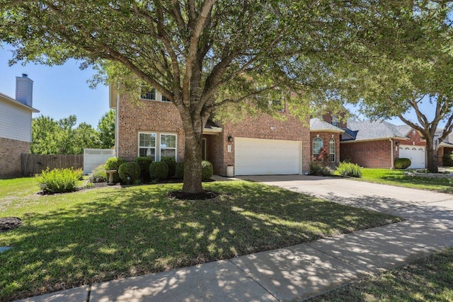 traditional-style house with fence, concrete driveway, a front yard, and brick siding