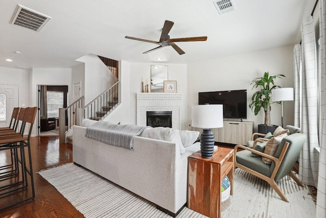 living area featuring stairway, a ceiling fan, wood finished floors, and visible vents