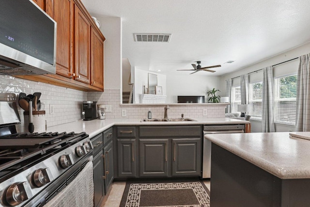 kitchen with visible vents, decorative backsplash, ceiling fan, a sink, and stainless steel appliances