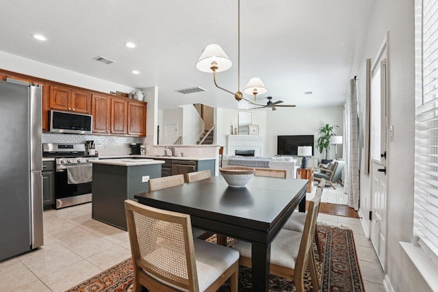 kitchen with visible vents, a fireplace, a center island, appliances with stainless steel finishes, and backsplash