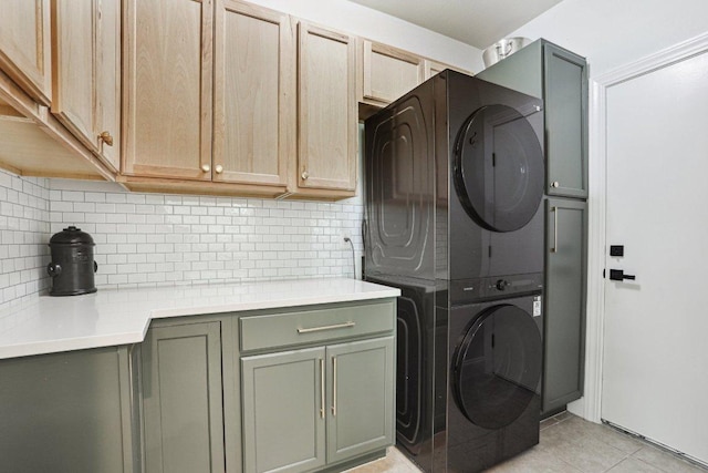washroom featuring cabinet space, stacked washing maching and dryer, and light tile patterned floors