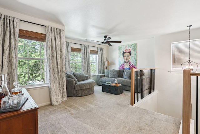 living area featuring baseboards, carpet, and a ceiling fan