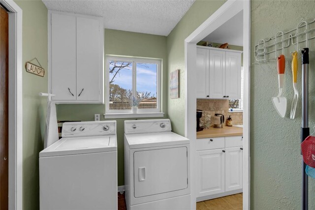 1309 E Brown St, Llano, TX 78643 - laundry area featuring washing machine and clothes dryer, cabinet space, a textured ceiling, light wood-style floors, and a textured wall