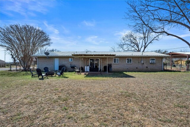 1309 E Brown St, Llano, TX 78643 - back of house featuring an outdoor fire pit, a metal roof, a yard, and brick siding