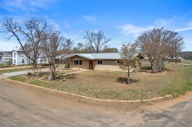 1309 E Brown St, Llano, TX 78643 - ranch-style house featuring a metal roof, concrete driveway, a front lawn, and brick siding