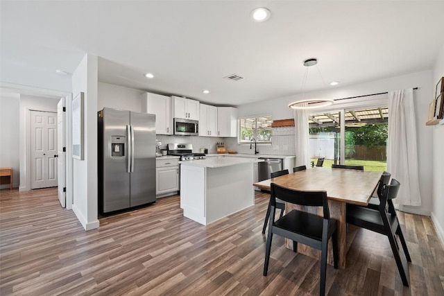 kitchen with wood finished floors, light countertops, a sink, backsplash, and stainless steel appliances