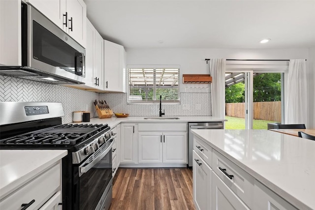 kitchen featuring light countertops, appliances with stainless steel finishes, a sink, and dark wood finished floors