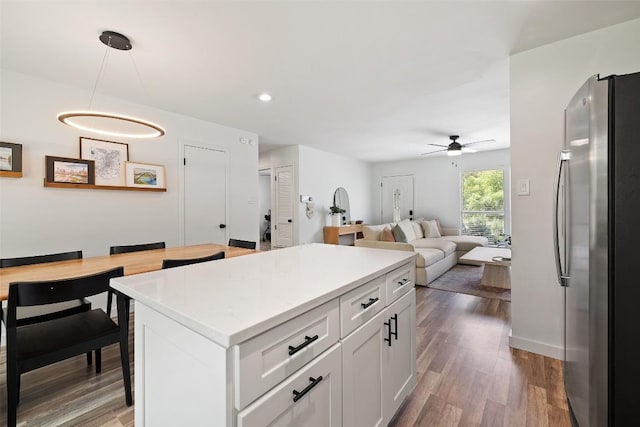 kitchen with white cabinets, ceiling fan, light countertops, freestanding refrigerator, and wood finished floors