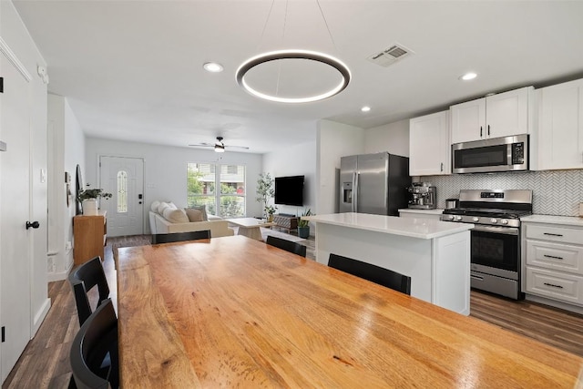 kitchen with visible vents, tasteful backsplash, white cabinets, dark wood-style floors, and stainless steel appliances
