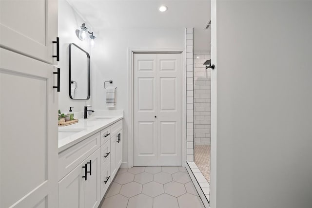 full bath featuring a sink, double vanity, tile patterned floors, recessed lighting, and tiled shower