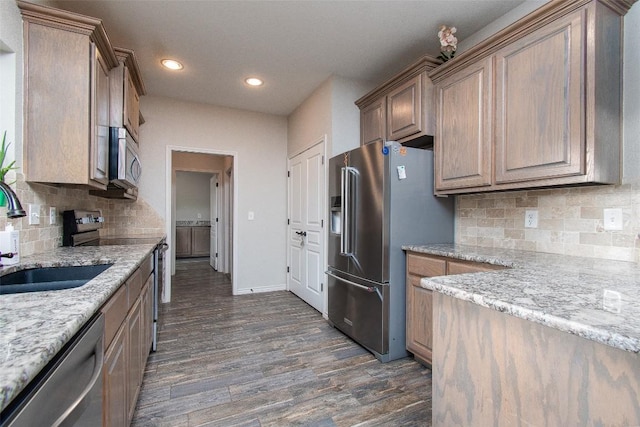 kitchen with backsplash, appliances with stainless steel finishes, dark wood finished floors, a sink, and recessed lighting