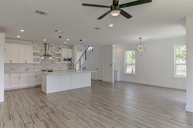 141 Awehi Ln, Bastrop, TX 78602 - kitchen featuring stainless steel microwave, wall chimney exhaust hood, healthy amount of natural light, backsplash, and recessed lighting