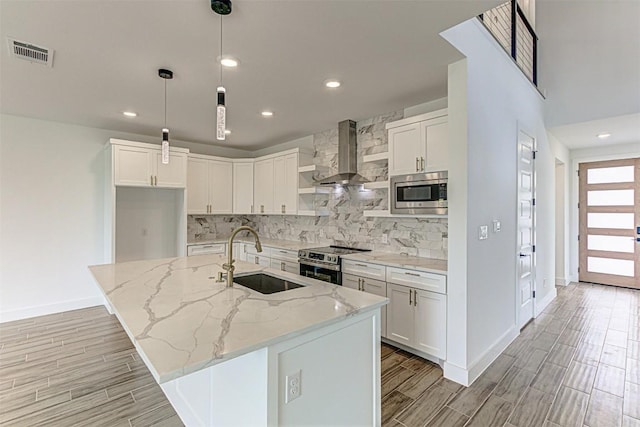 141 Awehi Ln, Bastrop, TX 78602 - kitchen with wall chimney exhaust hood, stainless steel appliances, wood tiled floors, tasteful backsplash, and recessed lighting